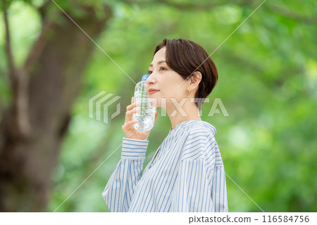 Woman holding a plastic bottle, fresh greenery Woman holding a plastic bottle, fresh greenery 116584756