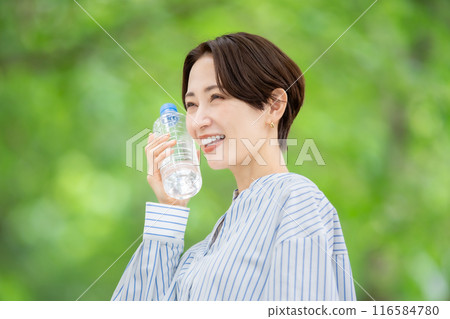 拿著塑膠瓶的女人，新鮮的綠色植物 116584780