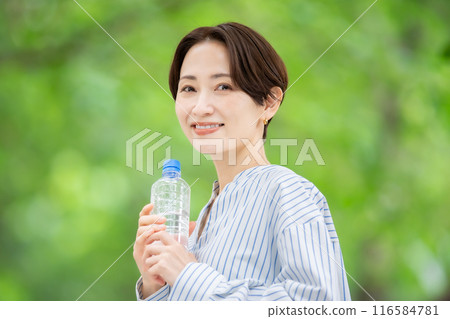 拿著塑膠瓶的女人，新鮮的綠色植物 116584781