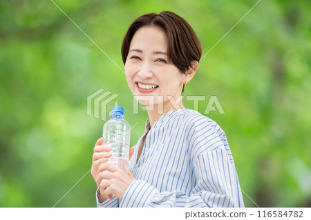 拿著塑膠瓶的女人，新鮮的綠色植物 116584782