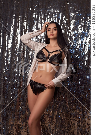 Stylish woman in leather lingerie standing in Christmas decorations 116585352