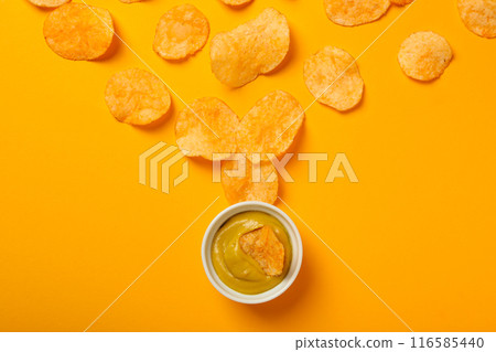 Potato chips with mustard on a yellow background Potato chips with mustard on a yellow background 116585440