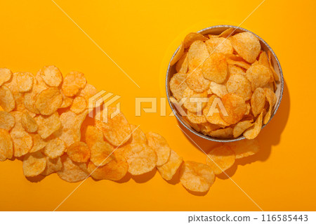 Potato chips in a bowl on a yellow background Potato chips in a bowl on a yellow background 116585443