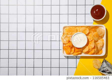 Potato chips in a bowl with sauces on a light background Potato chips in a bowl with sauces on a light background 116585463