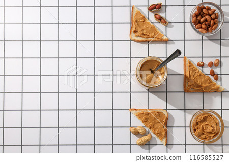 Peanut paste in a glass jar with a spoon, on a light background. Peanut paste in a glass jar with a spoon, on a light background. 116585527