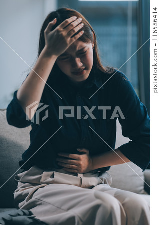 A woman with a cold with pills is treated at home chooses which drugs to take and self-medicates, checks the expiration date while sitting on the couch at home 116586414