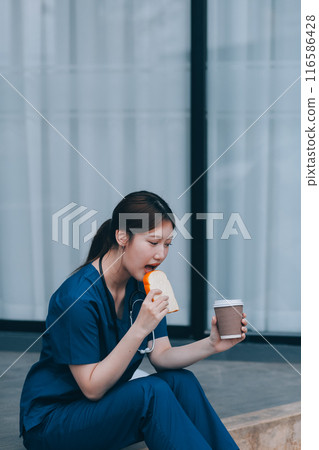 A cheerful woman in scrubs holds a clipboard, standing confidently before a modern hospital building, representing professional healthcare service. A cheerful woman in scrubs holds a clipboard, standing confidently before a modern hospital building, representing professional healthcare service. 116586428