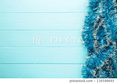 Christmas blue tinsel on blue wooden background. This has clipping path. Christmas blue tinsel on blue wooden background. This has clipping path. 116586693