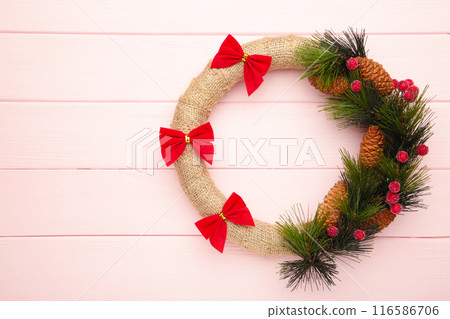 Green christmas wreath decorated with red bow on pink background. Thanksgiving Day. 116586706