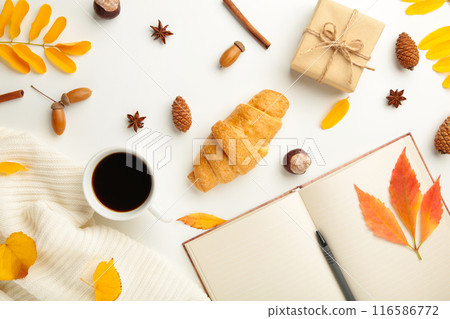 Autumn or winter composition. Cup of coffee, gift, dried autumn leaves, croissant on white background. Flat lay, top view, copy space Autumn or winter composition. Cup of coffee, gift, dried autumn leaves, croissant on white background. Flat lay, top view, copy space 116586772