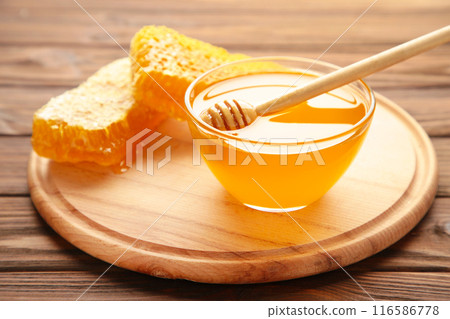 Bowl of honey with honeycomb on brown wooden table Bowl of honey with honeycomb on brown wooden table 116586778