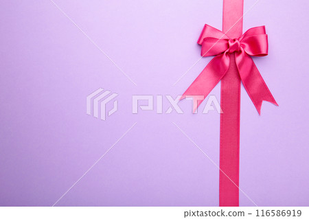 Pink pastel ribbon with bow on purple background. Pink pastel ribbon with bow on purple background. 116586919