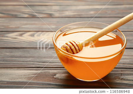 Bowl of honey on brown wooden background. Top view. 116586948