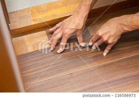 一名布藝工匠在翻新二手房時將地磚貼在走廊地板上。 一名布藝工匠在翻新二手房時將地磚貼在走廊地板上。 116586973