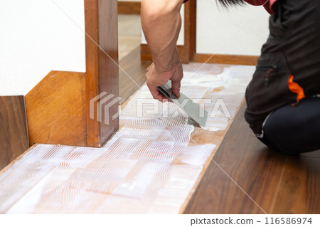 一名布藝工匠在翻新二手房時將地磚貼在走廊地板上。 116586974