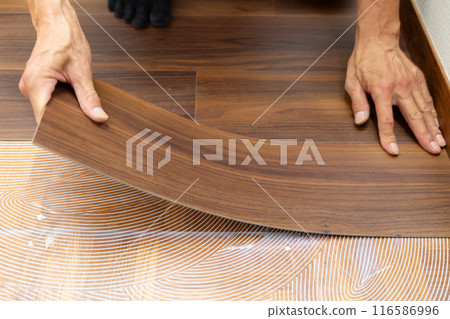 A wallpaper craftsman laying floor tiles on the hallway floor during the renovation of a used house 116586996