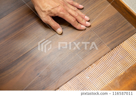 A wallpaper craftsman laying floor tiles on the hallway floor during the renovation of a used house A wallpaper craftsman laying floor tiles on the hallway floor during the renovation of a used house 116587011