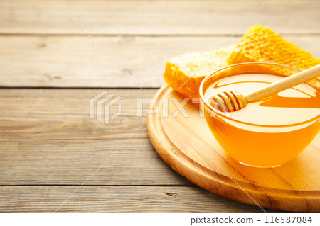 Bowl of honey with honeycomb on grey wooden table Bowl of honey with honeycomb on grey wooden table 116587084