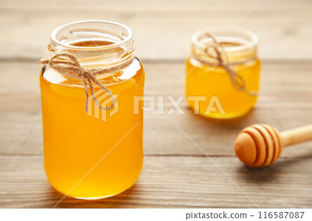 Jars of honey on grey wooden table 116587087