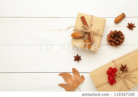 Autumn composition. Gift, autumn leaves, cinnamon sticks, anise stars, pine cones on white background. Autumn composition. Gift, autumn leaves, cinnamon sticks, anise stars, pine cones on white background. 116587180