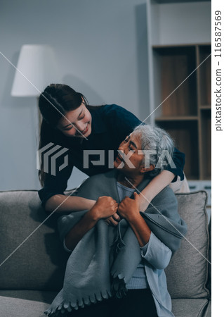 happy family Granddaughter takes care of her grandmother with warm cloths sitting on the sofa. happy family Granddaughter takes care of her grandmother with warm cloths sitting on the sofa. 116587569