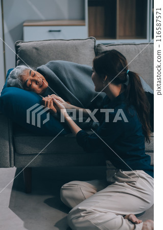 happy family Granddaughter takes care of her grandmother with warm cloths sitting on the sofa. 116587571