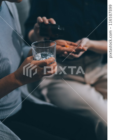 happy family Granddaughter takes care of her grandmother with warm cloths sitting on the sofa. 116587899