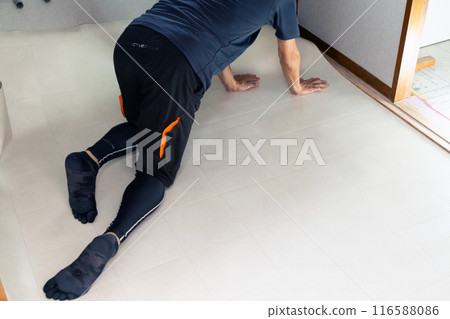 A wallpaper craftsman laying floor tiles on the wet area of a used house during renovation A wallpaper craftsman laying floor tiles on the wet area of a used house during renovation 116588086