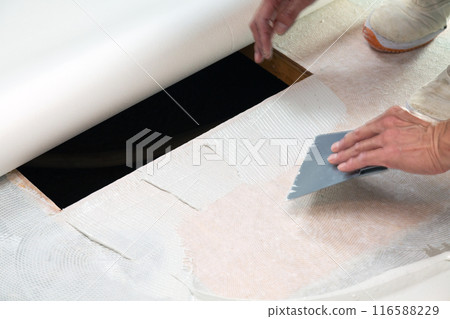 A wallpaper craftsman laying floor tiles on the wet area of a used house during renovation A wallpaper craftsman laying floor tiles on the wet area of a used house during renovation 116588229