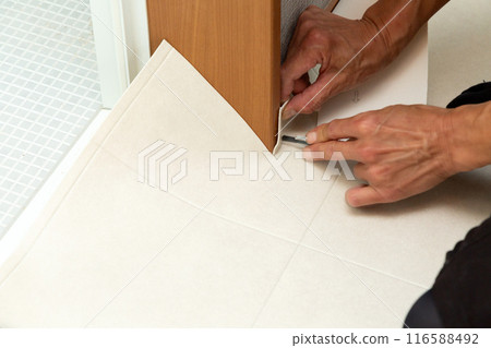 A wallpaper craftsman laying floor tiles on the wet area of a used house during renovation A wallpaper craftsman laying floor tiles on the wet area of a used house during renovation 116588492