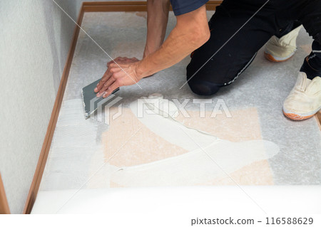 A wallpaper craftsman laying floor tiles on the wet area of a used house during renovation A wallpaper craftsman laying floor tiles on the wet area of a used house during renovation 116588629