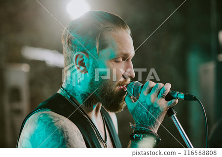 Closeup of young Caucasian man with beard on face enjoying singing rock song on stage in nightclub 116588808