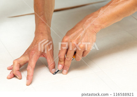 A wallpaper craftsman laying floor tiles on the wet area of a used house during renovation 116588921