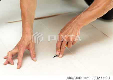 A wallpaper craftsman laying floor tiles on the wet area of a used house during renovation 116588925