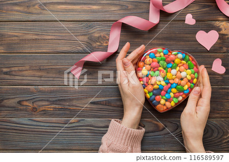 Female hands with delicious candies in box on color background Female hands with delicious candies in box on color background 116589597