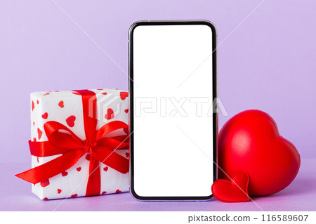 mobile phone with blank screen on colored background with hearts, calendar and gift box, valentine day concept perspertive view flat lay 116589607