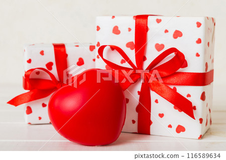 gift box with red bow and red heart on colored background. Perspective view. Flat lay gift box with red bow and red heart on colored background. Perspective view. Flat lay 116589634