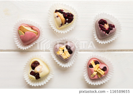 chocolate sweets in the form of a heart with fruits and nuts on a colored background. top view with space for text, holiday concept 116589655