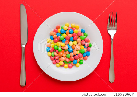 cutlery on table and sweet plate of candy. Health and obesity concept, top view on colored background 116589667