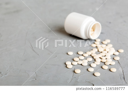 Medicine bottle and white pills spilled on a light background. Medicines and prescription pills flat lay background. White medical pills and tablets spilling out of a drug bottle Medicine bottle and white pills spilled on a light background. Medicines and prescription pills flat lay background. White medical pills and tablets spilling out of a drug bottle 116589777