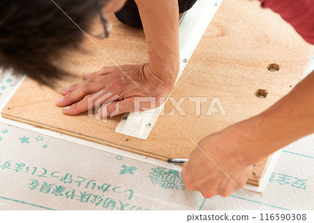 A wallpaper craftsman laying floor tiles on the wet area of a used house during renovation 116590308