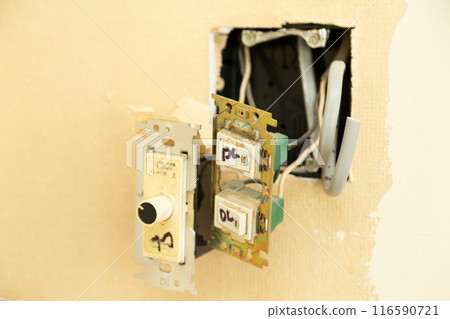 A light switch sticking out of the wall of an old house 116590721