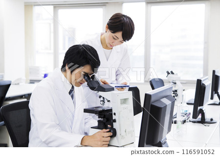 A researcher conducting an experiment in a laboratory A researcher conducting an experiment in a laboratory 116591052