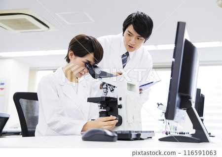 A researcher conducting an experiment in a laboratory A researcher conducting an experiment in a laboratory 116591063