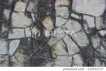 Granite stones darkened with time and placed in old masonry 116591317