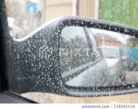 Dirt spattered on the outside of the car window next to the side mirror. Weather phenomena in the urban environment 116591529