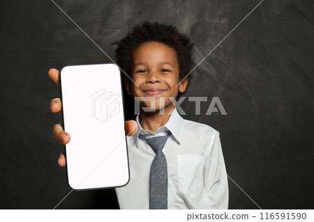 Smiling little school boy holding cell phone in his hand presenting smartphone empty screen display 116591590