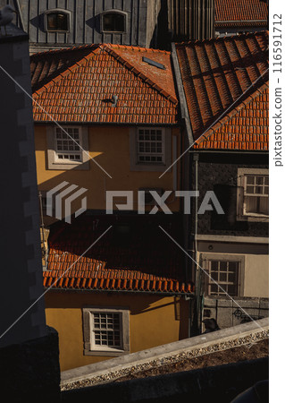 A row of buildings with red tile roofs and beige brick facades 116591712