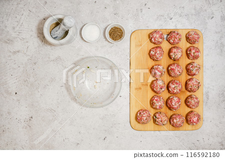 Top view of raw meatballs on wooden cutting board 116592180