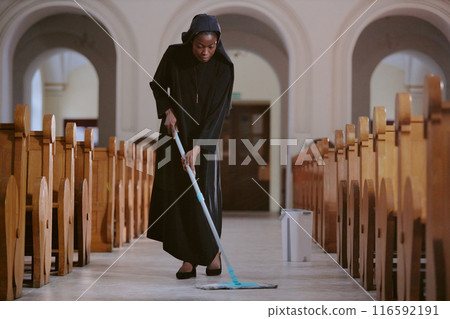 Long shot of young African American nun wiping floor at nave in Catholic church with use of mop, copy space Long shot of young African American nun wiping floor at nave in Catholic church with use of mop, copy space 116592191